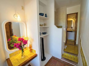 Ein Badezimmer mit Spiegel, Waschbecken, Blumen in einer Vase, Heizung und Duschbereich.