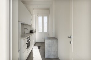 A compact kitchen with white cabinetry, a built-in oven, and a small island.