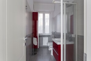 A modern bathroom with a shower, toilet, and sink.