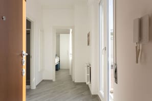 A hallway with a wooden door, a radiator, and a wall-mounted light fixture.