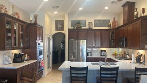 A modern kitchen with dark wooden cabinets, stainless steel appliances, and a central island with bar stools.