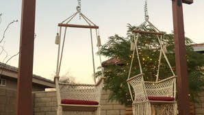 A fire pit with hanging swing seats under a wooden pergola.