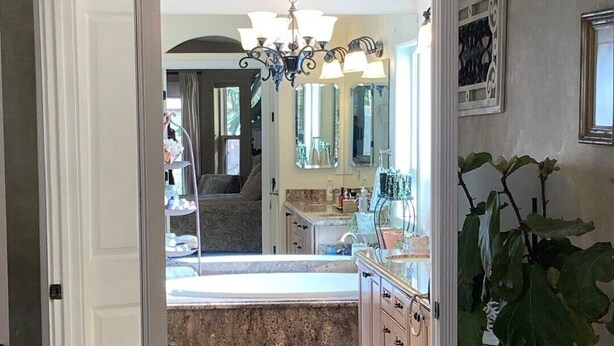 A bathroom with a large mirror, a sink, and a shower area.