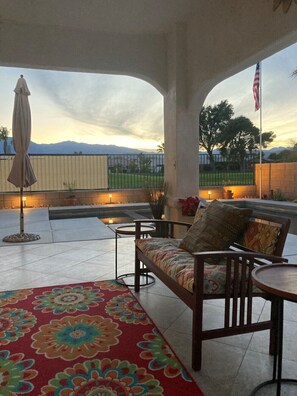 Eine Terrasse im Freien mit einer Couch, Stühlen und einem gemusterten Teppich.