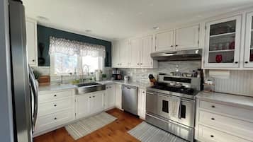 Enjoy cooking in this well-equipped kitchen with a dishwasher, oven, and microwave, plus a cabinet and window with a lace curtain.