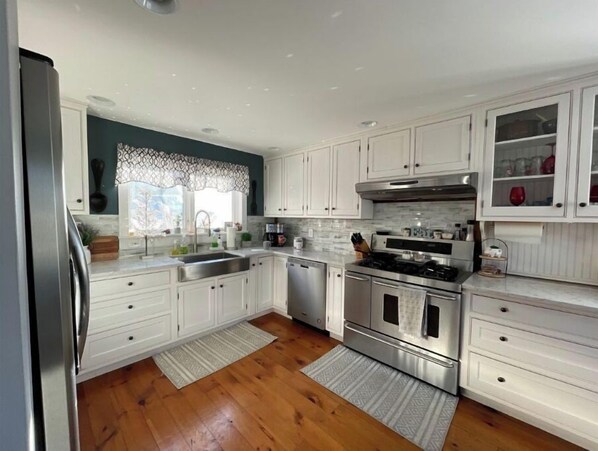 Enjoy cooking in this well-equipped kitchen with a dishwasher, oven, and microwave, plus a cabinet and window with a lace curtain.