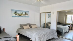 A bedroom with a bed, a ceiling fan, a painting of palm trees, and a large mirror. - 🌵 Tucson Desert Oasis – 6BR-5BA Home near Golf Courses, University & Shopping (Tucson)