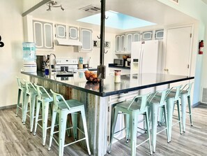 Una cocina moderna con una isla central, taburetes de bar y armarios blancos.