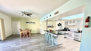 A spacious kitchen with a central island, bar stools, and a dining area with wooden chairs. - 🌵 Tucson Desert Oasis – 6BR-5BA Home near Golf Courses, University & Shopping (Tucson)