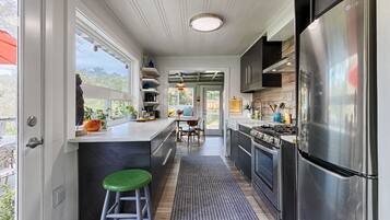 A modern kitchen with a stainless steel refrigerator, a dining area with a view, and a bar stool.