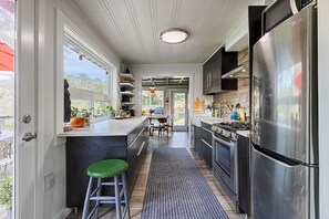Una cocina moderna con un refrigerador de acero inoxidable, un área de comedor con vistas y un taburete de bar.