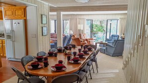 Un vaste espace dédié à la salle à manger, avec une longue table en bois dressée pour le repas, entourée de sièges confortables.