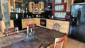A modern kitchen with wooden cabinets, a black refrigerator, and a dining table with chairs.