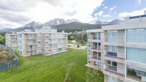 A modern apartment complex with multiple floors, balconies, and a view of mountains in the background. - Pacífico Apartamentos Ribera (Ushuaia)