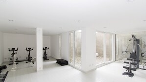 A modern gym with various exercise equipment, large windows, and a clean, minimalist design. - Pacífico Apartamentos Ribera (Ushuaia)