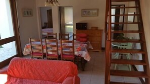 Ein Essbereich mit Tisch für vier Personen, einem Holzschrank und einer Leiter, die zu einem Balkon führt.