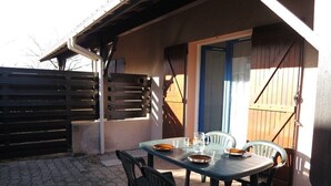 Un patio con mesa y sillas, cerca de madera y una puerta.