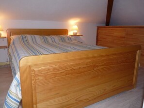 Uma cama de madeira com colcha listrada em quarto com duas luminárias de cabeceira.