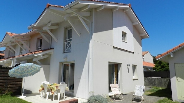 A two-story house with a patio area, a table with chairs, and a small garden. - Beautiful duplex apartment of around 55m² for 4 people (BISCARROSSE)