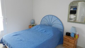 A bedroom with a bed, a nightstand, a lamp, a mirror, and a wardrobe. - Beautiful duplex apartment of around 55m² for 4 people (BISCARROSSE)