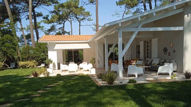 A modern house with a covered patio area, white outdoor furniture, and a well-maintained lawn. - pleasant villa of around 130m² for 7 people (BISCARROSSE)