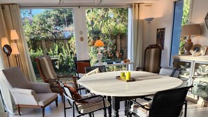 A dining area with a round table, chairs, and a view of the outdoors. - pleasant villa of around 130m² for 7 people (BISCARROSSE)