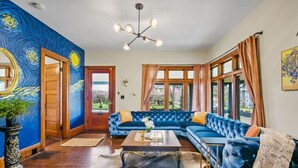 A room with a blue velvet sofa, a wooden coffee table, and a chandelier. - Casa Van Gogh: a Historic N. Slope retreat (Tacoma)