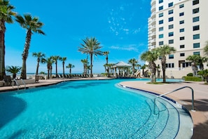 A clear blue pool surrounded by palm trees and lounge chairs, with a building in the background. - Direct Gulffront, Free Beach Service, Tony Hobbs, Owner 1104-1204-1804-1904 (Pensacola)