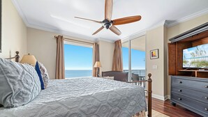 Ein Schlafzimmer mit Bett, Deckenventilator, Fernseher und Meerblick.