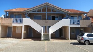A two-story building with a central staircase, balconies, and a parking area.