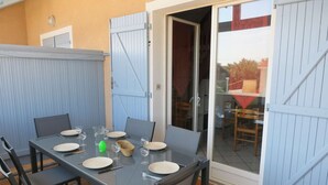 Zona pranzo con tavolo imbandito per quattro persone, sedie e una porta scorrevole in vetro che dà su uno spazio all'aperto.