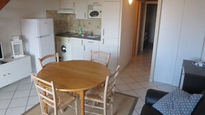 A compact kitchen with white cabinets, a microwave, and a washing machine. There is a wooden dining table with chairs. - Apartment on the 1st floor of 45m² for 6 people (BISCARROSSE)