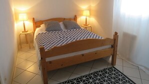 A neatly made bed with a checkered bedspread, two bedside lamps, and a framed picture on the wall. - Apartment on the 1st floor of 45m² for 6 people (BISCARROSSE)