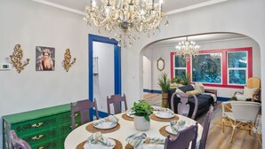Ein Essbereich mit einer Chandelier, einem runden Tisch für vier Personen und einer grünen Kommode.