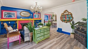 Ein Zimmer mit lebendigen Farben, einem Kamin, einer Chandelüster und verschiedenen dekorativen Elementen.