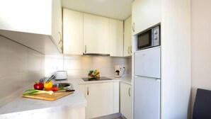 Eine kleine Küche mit weißen Schränken, einer Mikrowelle, einer Kaffeemaschine und einem Toaster.