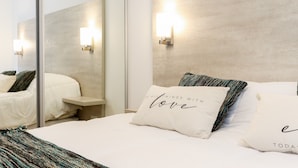 Een moderne hotelkamer met een groot bed, twee nachtkastjes, een spiegel en wandlampen.