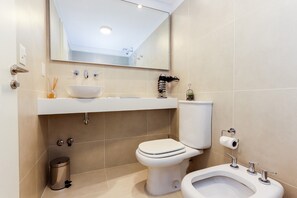 A modern bathroom with a white sink, toilet, bidet, and bidet seat. - Pacífico Apartamentos Terrazas (Ushuaia)