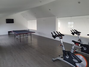 A spacious room with a ping pong table and two stationary bikes. - Pacífico Apartamentos Terrazas (Ushuaia)