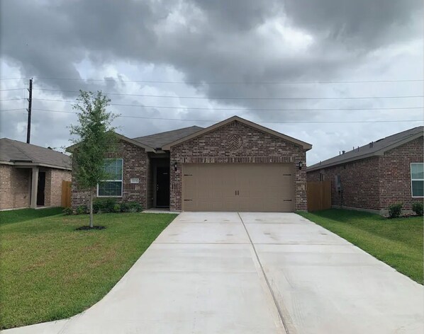 A residential building with a garage, a driveway, and a small tree. - ENTIRE HOME JUST 10 MINS from IAH, 20 Miles DWNTWN (Humble)