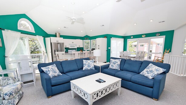 A living room with two blue sofas, a white coffee table, and a kitchen in the background. - Semi-Soundfront, Private Pool, Hot Tub, Gas grill, MS9, Mango Manor (Corolla)