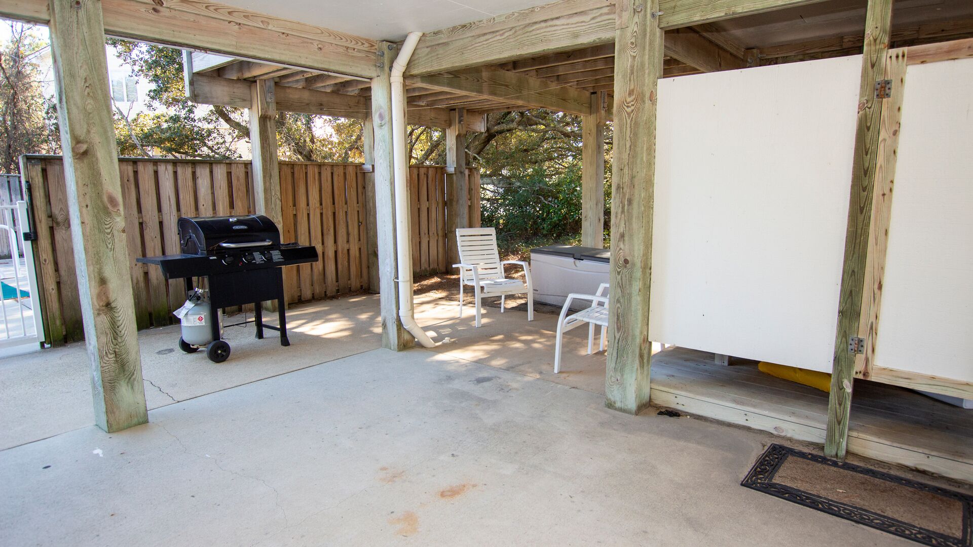 Un patio couvert équipé d’un barbecue, de sièges d’extérieur et d’un tableau blanc.