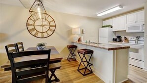 Een moderne keuken met witte kasten, een centraal eiland en een hanglamp met een geometrisch ontwerp.