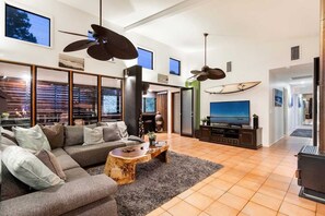 Relax in this stylish living room with a sofa, coffee table, and flat-screen TV, plus a fireplace and large windows with blinds.