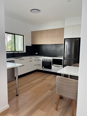 Enjoy meals in the well-lit kitchen with an oven, stainless steel refrigerator, and sleek cabinetry.