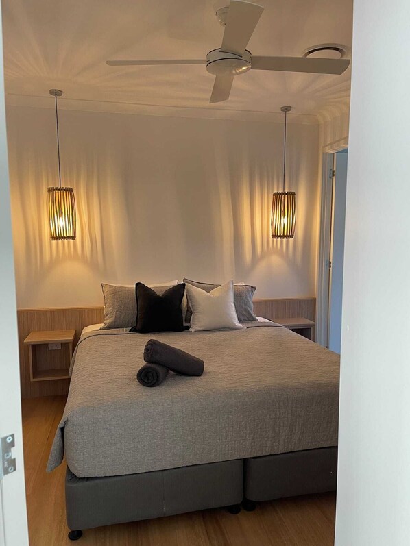Relax in a serene bedroom with a large bed, pendant lights, and a ceiling fan.
