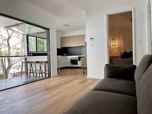Relax in this open-plan living space with a sofa, dining area, and kitchen, offering a bright and airy atmosphere.