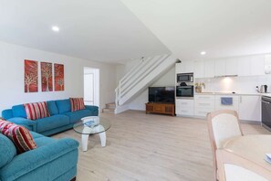 Relax in this stylish living space with a sofa, glass coffee table, and modern kitchen.
