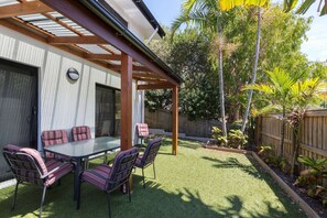 Relax in a serene outdoor space surrounded by lush greenery and a wooden pergola.