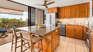 Una cocina con armarios de madera, un refrigerador de acero inoxidable y una isla grande con taburetes de bar.